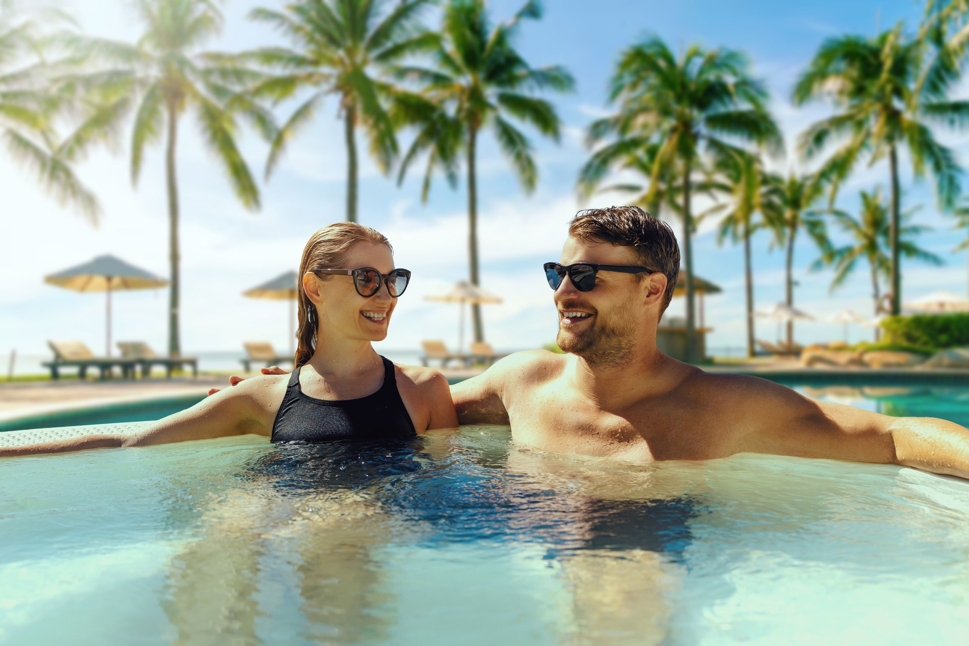 couple relaxing in hot tub by swimming pool at tropical resort