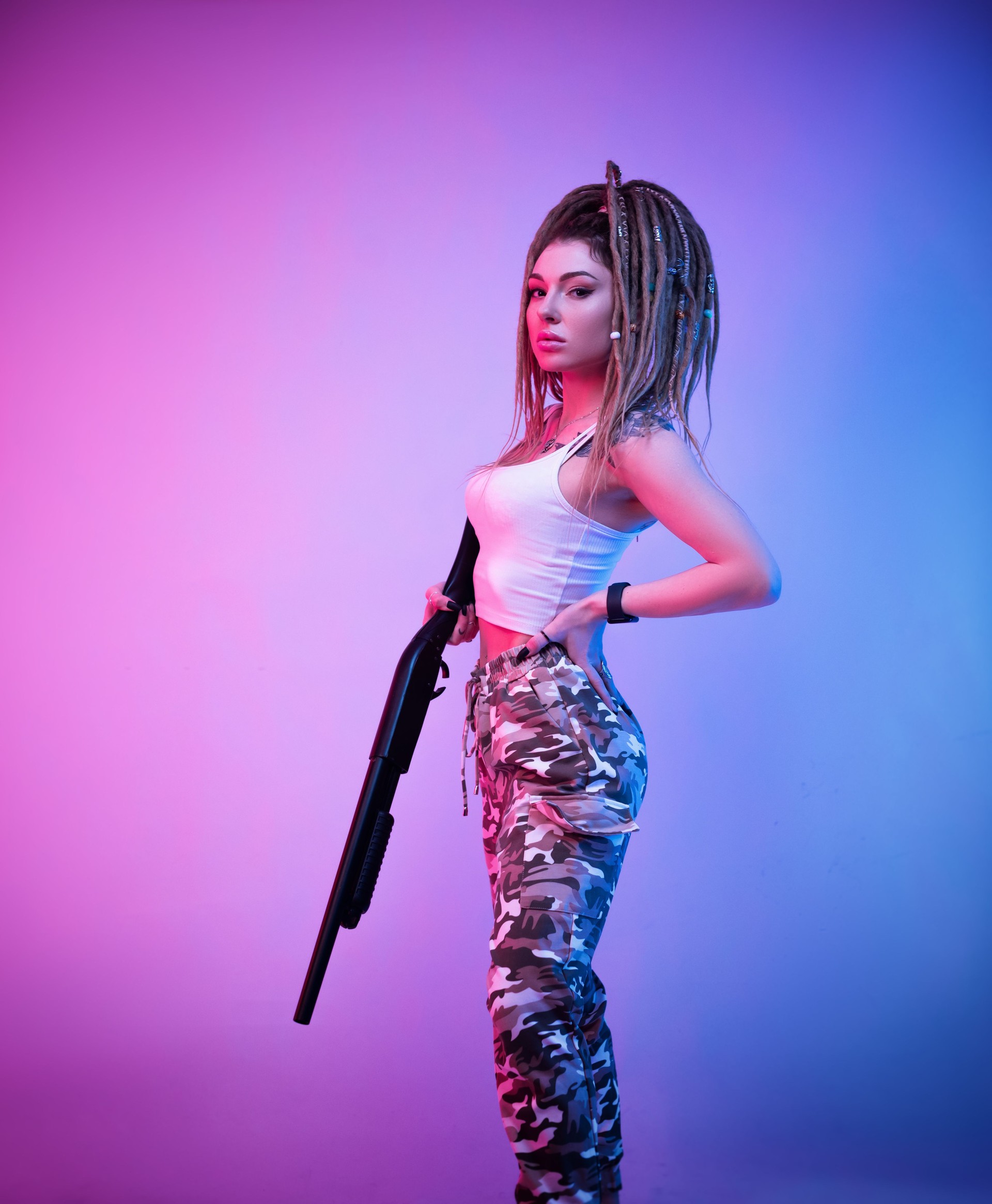 a cheeky girl with braided dreadlocks on her head in neon light with an gun